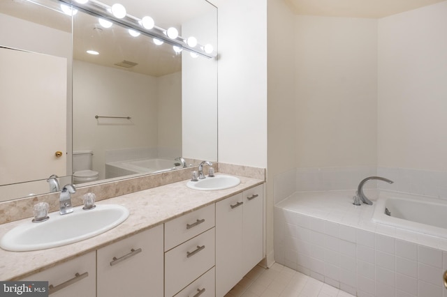 bathroom with tile patterned flooring, vanity, a relaxing tiled tub, and toilet