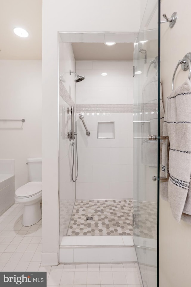 bathroom featuring tile patterned flooring, toilet, and walk in shower