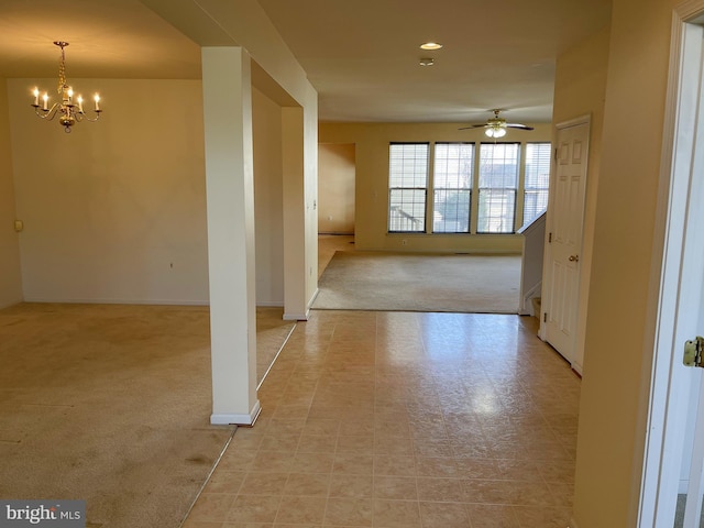 interior space featuring light carpet, baseboards, and ceiling fan with notable chandelier