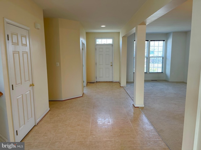 foyer featuring baseboards and light colored carpet