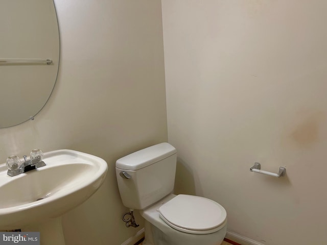 half bath with a sink, toilet, and baseboards