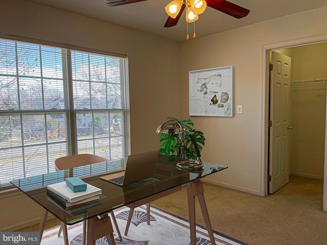 office space with light carpet, baseboards, and a ceiling fan