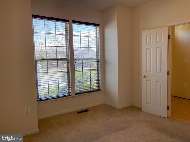 carpeted spare room featuring visible vents and baseboards