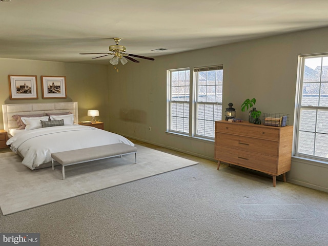 carpeted bedroom featuring a ceiling fan, visible vents, baseboards, and multiple windows