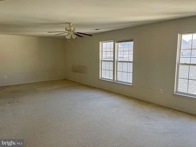 carpeted empty room featuring a ceiling fan, a healthy amount of sunlight, visible vents, and baseboards