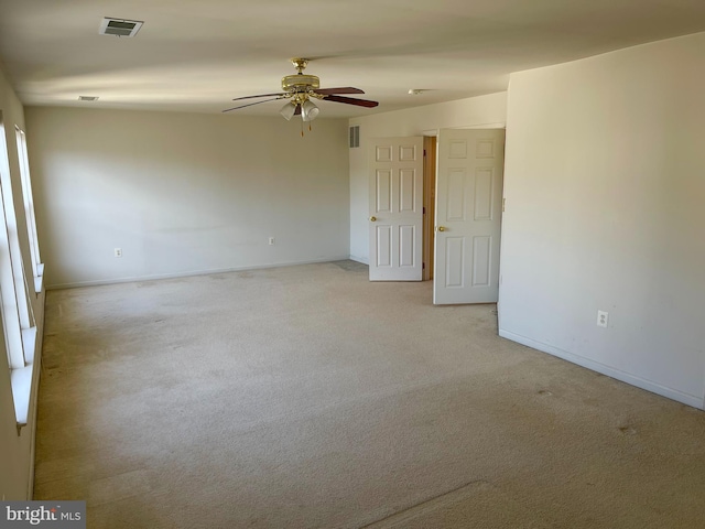 spare room featuring baseboards, visible vents, a ceiling fan, and light colored carpet