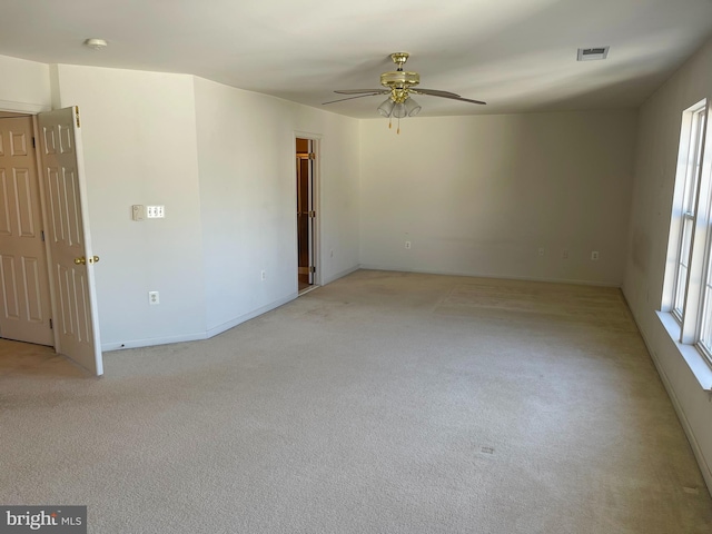 spare room featuring light carpet, visible vents, and a ceiling fan