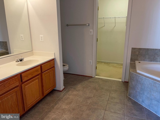 full bathroom featuring toilet, a garden tub, a spacious closet, and vanity