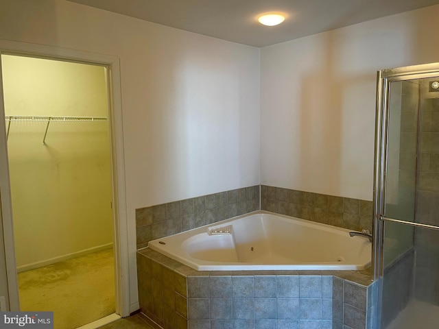 full bathroom featuring a shower stall, a walk in closet, and a bath