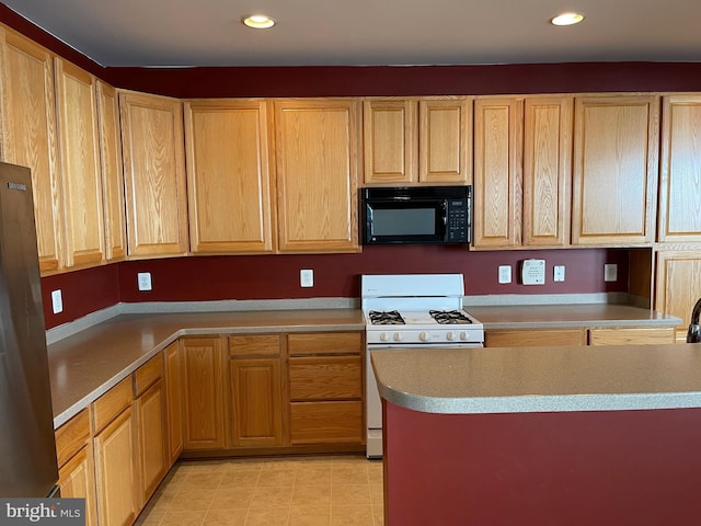 kitchen with recessed lighting, black microwave, light brown cabinetry, and white gas range