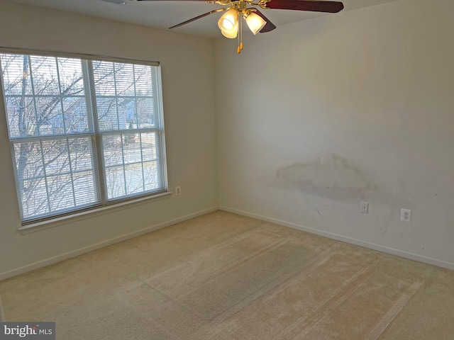 carpeted empty room featuring a healthy amount of sunlight, ceiling fan, and baseboards