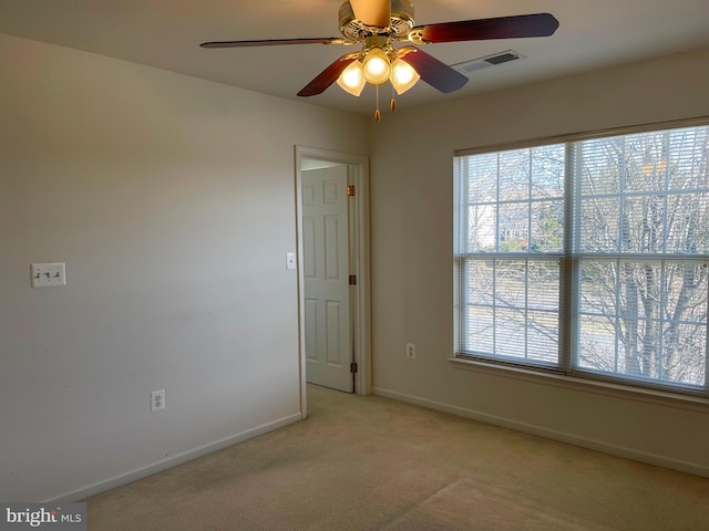 empty room featuring plenty of natural light, visible vents, baseboards, and light colored carpet