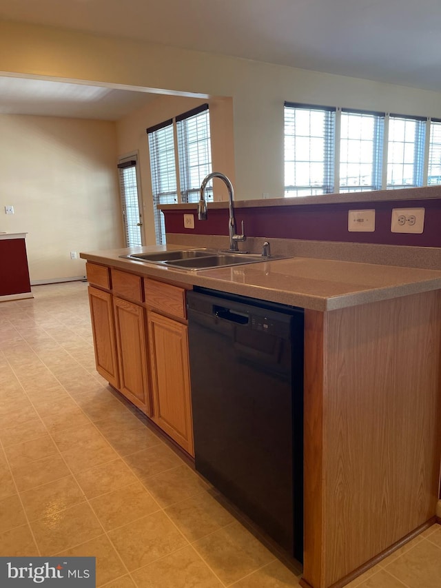 kitchen featuring black dishwasher, light countertops, a sink, and a center island with sink