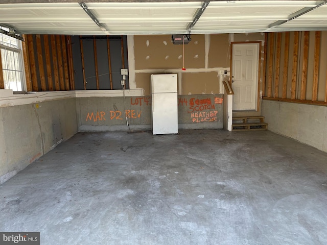 garage with a garage door opener and freestanding refrigerator