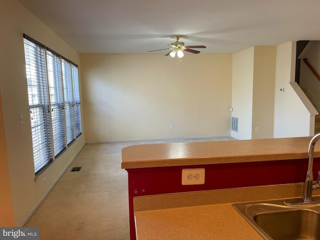 kitchen with light carpet, a sink, visible vents, and ceiling fan