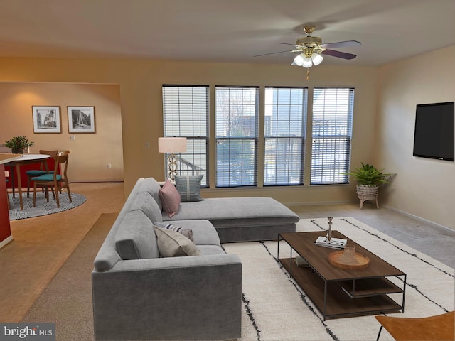 living room featuring a ceiling fan and baseboards