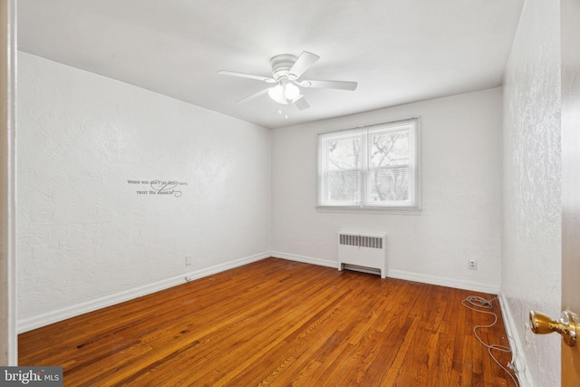 unfurnished room featuring radiator, hardwood / wood-style floors, and ceiling fan