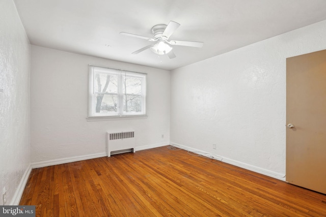 spare room with ceiling fan, radiator heating unit, and wood-type flooring