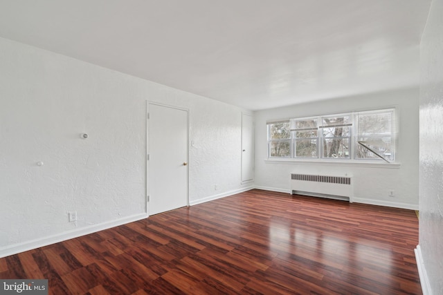 interior space with radiator heating unit and dark hardwood / wood-style flooring