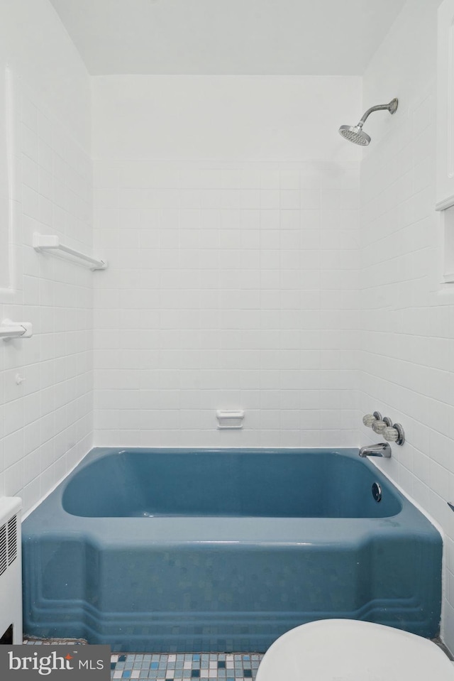 bathroom with tiled shower / bath combo, radiator heating unit, and toilet