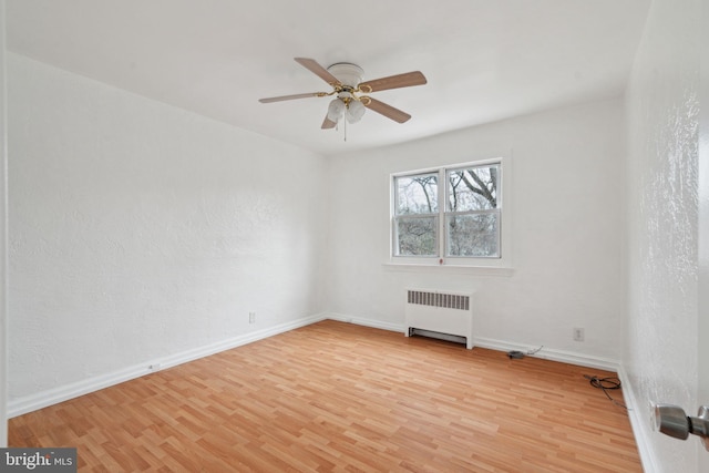 spare room with radiator, ceiling fan, and light hardwood / wood-style flooring