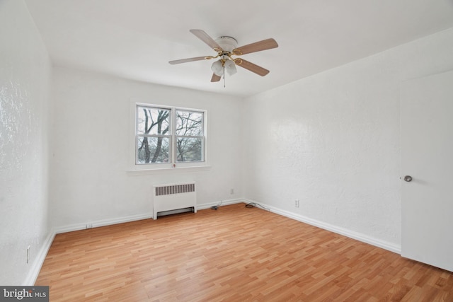 empty room with radiator heating unit, light hardwood / wood-style floors, and ceiling fan