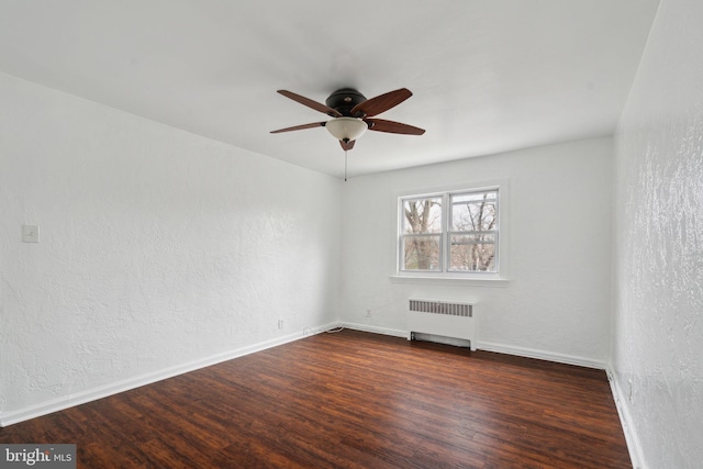 unfurnished room with dark hardwood / wood-style floors, radiator heating unit, and ceiling fan