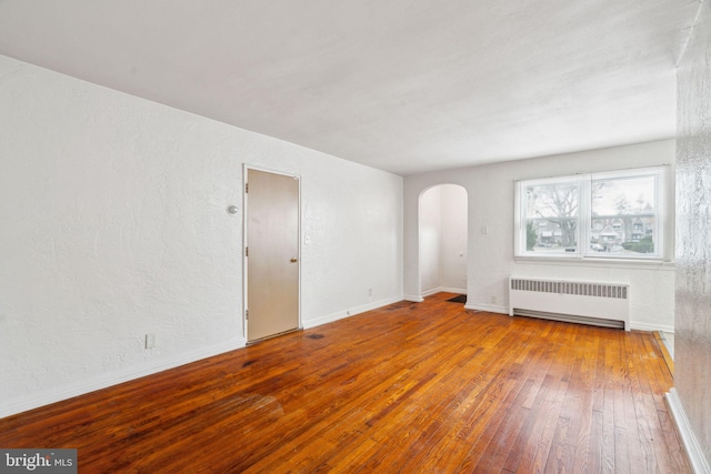 unfurnished living room featuring radiator and hardwood / wood-style floors