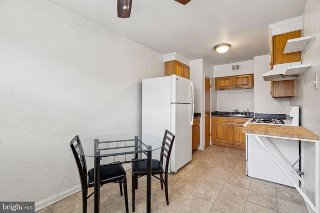 kitchen with white refrigerator, ceiling fan, and gas range