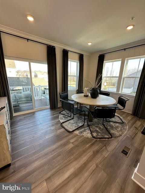 dining area with wood-type flooring, crown molding, and a wealth of natural light