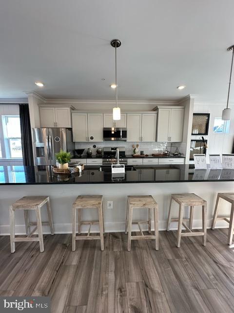 kitchen with a kitchen breakfast bar, backsplash, stainless steel appliances, and pendant lighting