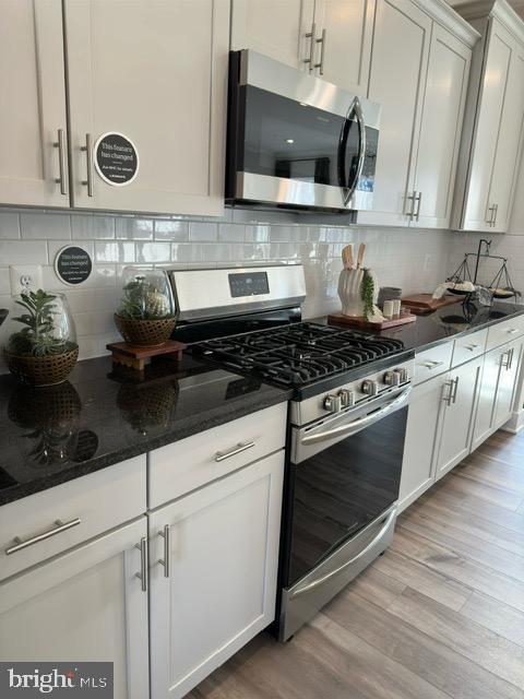 kitchen featuring white cabinets, decorative backsplash, light hardwood / wood-style floors, and stainless steel appliances