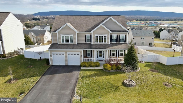 view of front of property with covered porch, a mountain view, a garage, and a front lawn