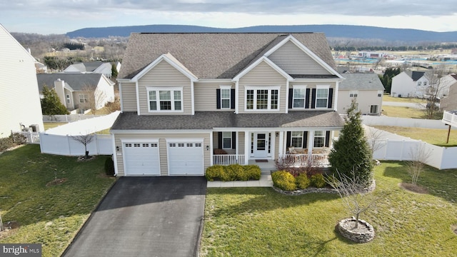 view of front facade featuring a mountain view, a front lawn, covered porch, and a garage