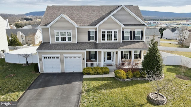 view of front of house featuring a mountain view, a porch, a garage, and a front yard