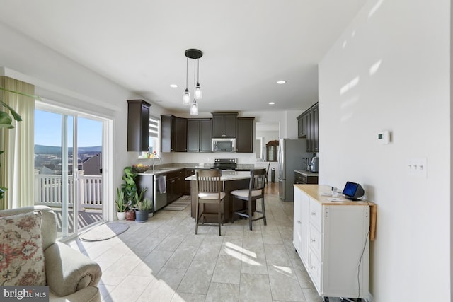 kitchen with dark brown cabinets, stainless steel appliances, sink, a center island, and hanging light fixtures