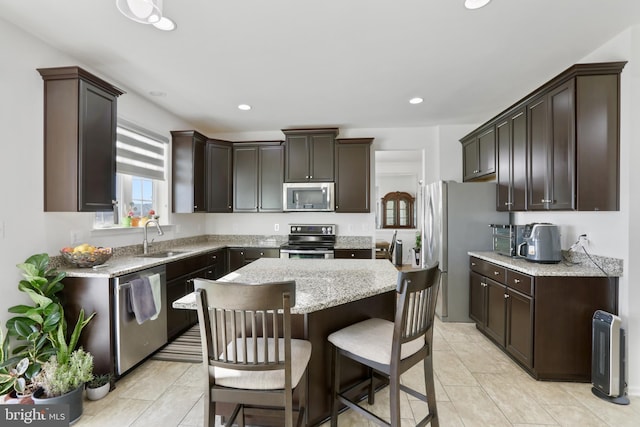 kitchen with a center island, stainless steel appliances, dark brown cabinetry, and sink