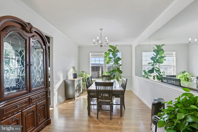 dining room featuring light wood-type flooring, an inviting chandelier, and crown molding