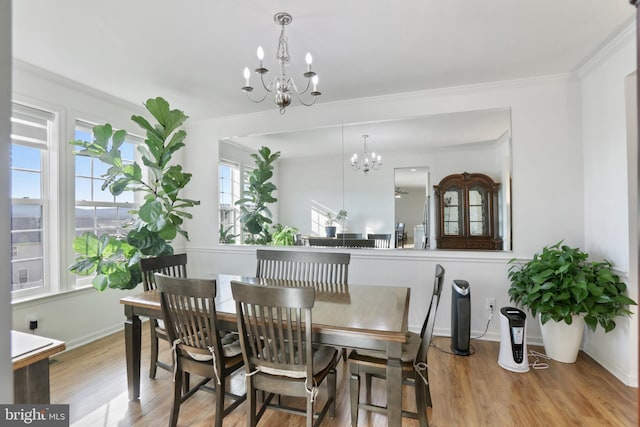 dining area with ornamental molding, light hardwood / wood-style flooring, and a notable chandelier