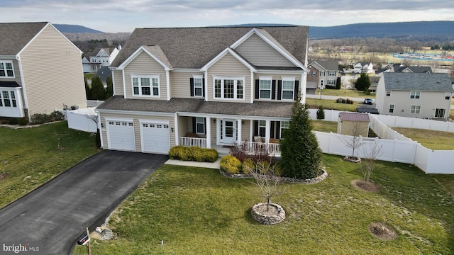 view of front facade with a mountain view, a front lawn, covered porch, and a garage