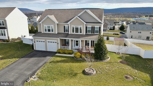 view of front of home with covered porch, a mountain view, a garage, and a front yard