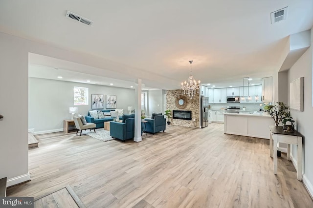 living room featuring a fireplace, an inviting chandelier, and light hardwood / wood-style flooring