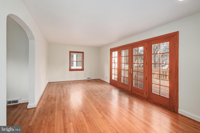 spare room with french doors, a wealth of natural light, and light hardwood / wood-style floors