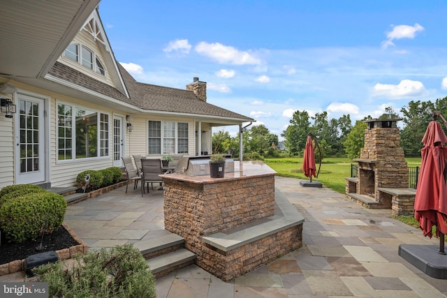 view of patio / terrace featuring exterior kitchen and an outdoor stone fireplace