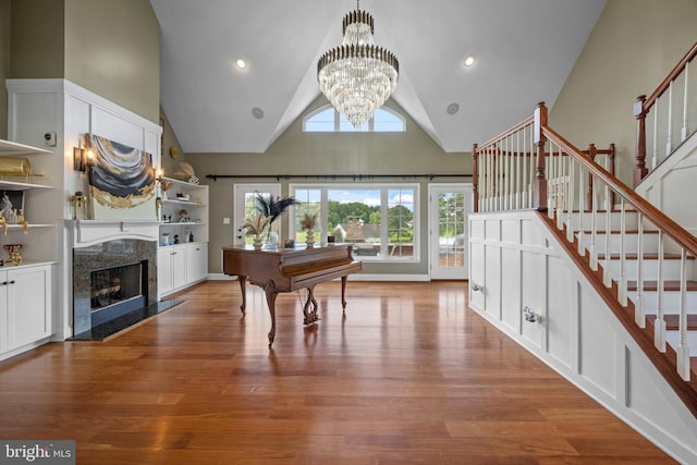 misc room with a fireplace, a chandelier, high vaulted ceiling, and light hardwood / wood-style flooring