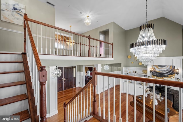 stairs with a notable chandelier, wood-type flooring, and a towering ceiling