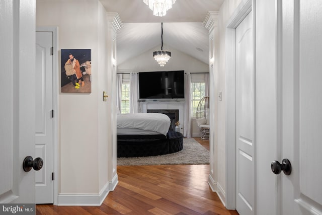 hall featuring hardwood / wood-style flooring, lofted ceiling, and an inviting chandelier