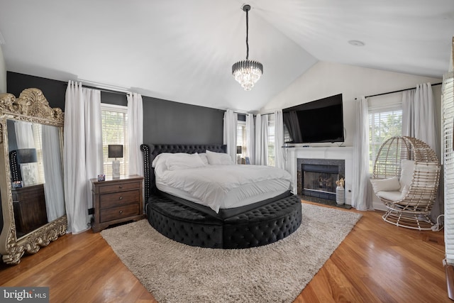 bedroom with vaulted ceiling, wood-type flooring, and an inviting chandelier