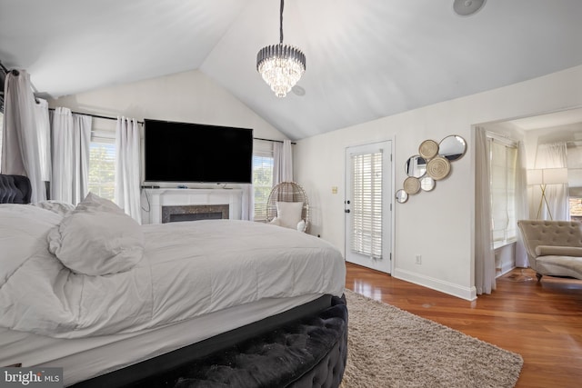 bedroom with vaulted ceiling, an inviting chandelier, wood-type flooring, and multiple windows