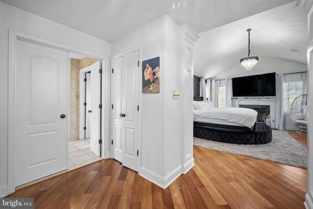 unfurnished bedroom with an inviting chandelier, light hardwood / wood-style flooring, and lofted ceiling